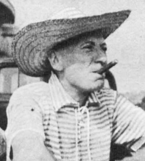 William Hartnell in a sun hat, smoking a cigar