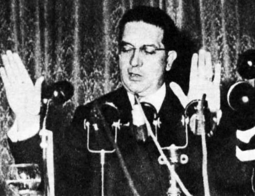 A man stands behind microphones